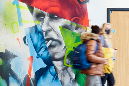 People walking in front of art wall